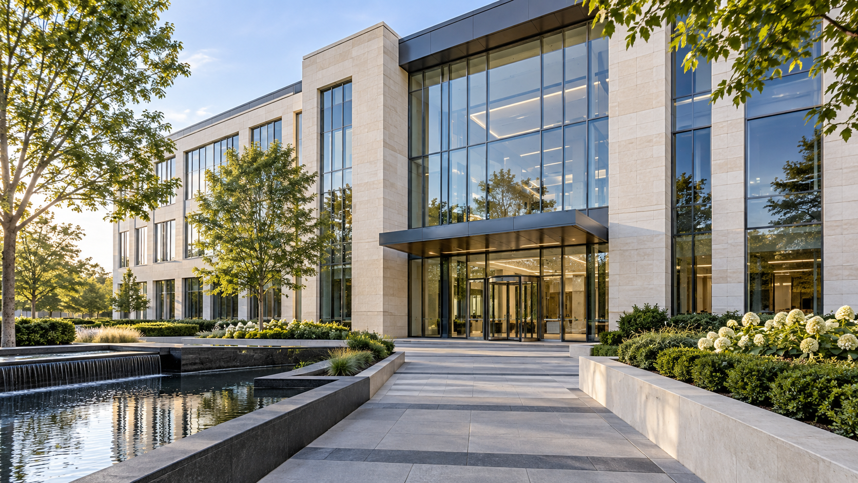 Modern stone-and-glass commercial building with a landscaped entrance and reflecting pool